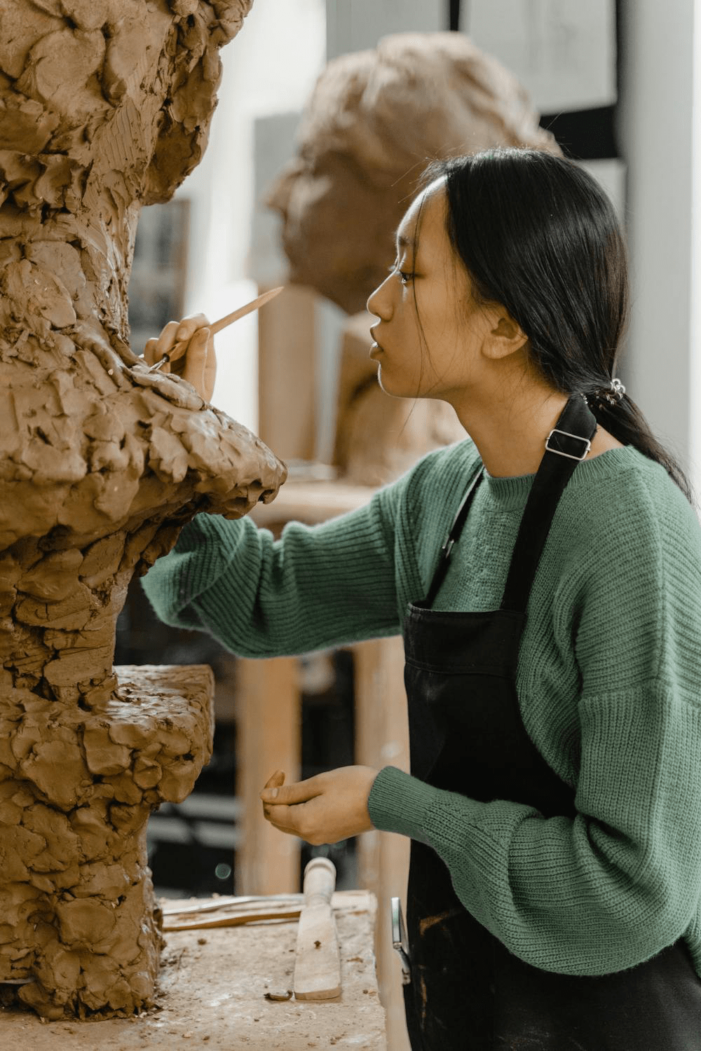 Female sculptor shaping a clay figure in a studio.