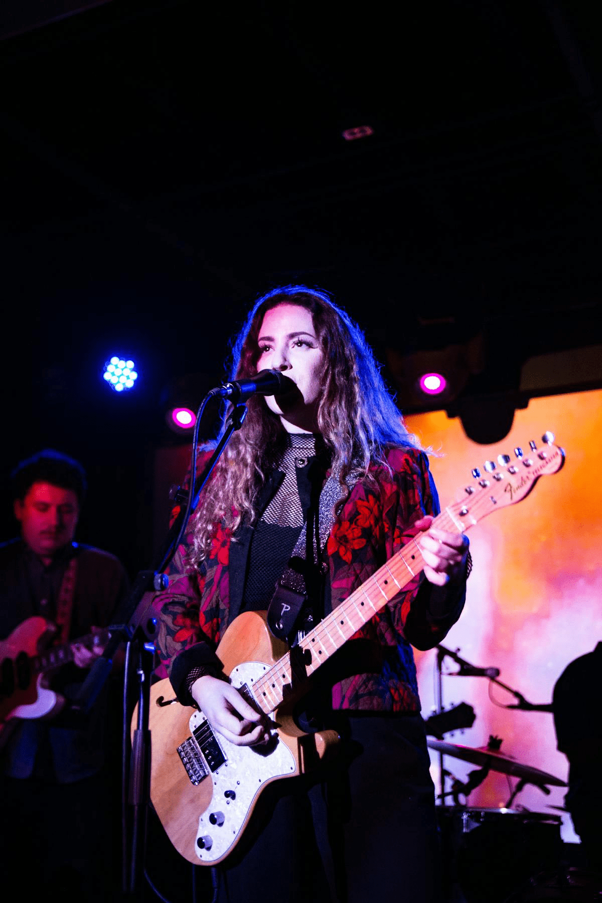 Female musician performing live on stage playing an electric guitar.