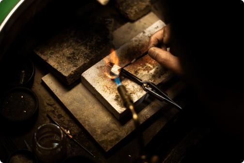 Close-up of hands using a blowtorch to craft jewellery on a workbench, representing skilled artisans beyond Murray.