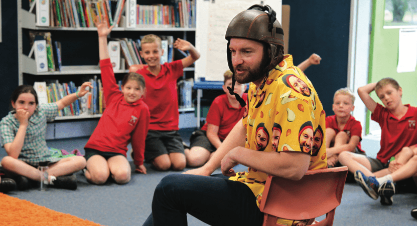 Male creative wearing a colorful shirt engaging with children in a classroom during an arts activity in Murray and North East Victoria.